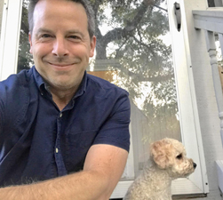 Jeffrey Hermann - white man with navy shirt and small white dog near window