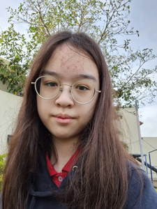 female with large wire-framed glasses and blue sweatshirt hoodie